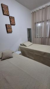 a bedroom with two beds and a window with curtains at Santos & Oliveira in Diamantina