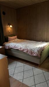 a bed in a bedroom with a wooden wall at Steineveien 300 in Vestvågøya +15 photos