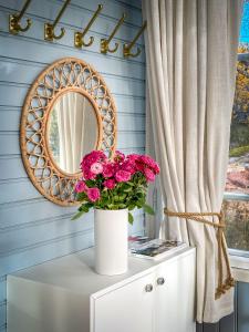a mirror and a vase with flowers on a cabinet at Villa Maija 1 Eastside in Hanko