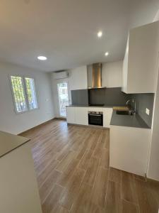 eine Küche mit weißen Schränken und einem Holzboden in der Unterkunft Guesthouse Cervantes - Rooms cerca del centro de Granada in Granada