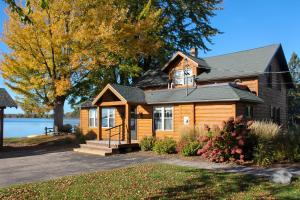 una casa de madera con un árbol y un lago en Lakefront Cabin with Shared Beach in Cecil!, en Shawano