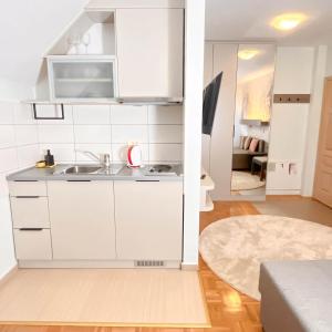 a white kitchen with a sink and a living room at Vila Danica in Jahorina
