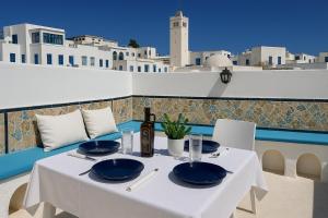 a white table with blue plates and bottles on a balcony at Dar Mima rooftop sea view in Sidi Bou Saïd