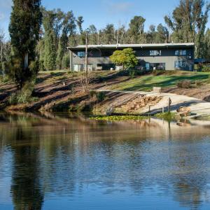 a building on a hill next to a body of water at Saladin Lodge in Narbethong