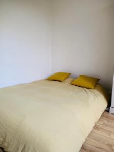 ein weißes Bett mit zwei gelben Kissen darauf in der Unterkunft Charmant appartement vue jardin in Neuilly-sur-Seine