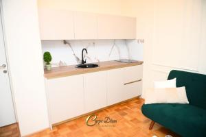 a kitchen with white cabinets and a green couch at Carpe Diem Spa Apartman in Teslić