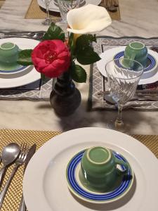 uma mesa com pratos e uma flor vermelha num vaso em Chalé alpino em canela rs todo mobiliado com cozinha lareira split Wi-Fi 2 quartos perto do centro em Canela