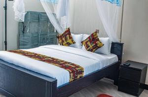 a bedroom with a large bed with white sheets and pillows at Sqore Lounge in Gulu