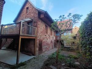 a brick house with a balcony and a staircase at Domaine au Grès des Pierres in Flexbourg