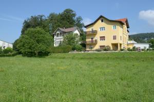 a large yellow house in a field of grass at Villa Wurzer in Velden am Wörthersee