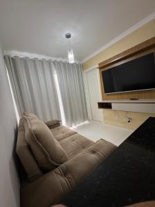 a living room with a couch and a flat screen tv at Casa Arruda Climatizada 5 proximo shopping boulevard in Vitória da Conquista