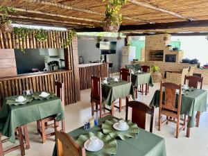 a restaurant with green tables and chairs and a kitchen at Villa Ferradura Mar in Búzios