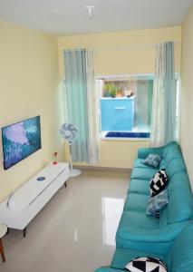 a living room with a green couch and a window at Casa Balneário Arpoador in Peruíbe
