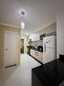 a kitchen with a white refrigerator and a black counter top at Casa Arruda Climatizada 5 proximo shopping boulevard in Vitória da Conquista