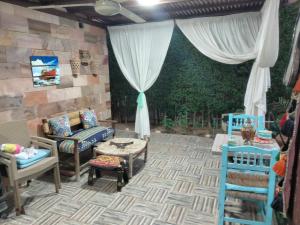 a patio with chairs and a table and curtains at Villa hossam elkady in Maḩaţţat Wardān