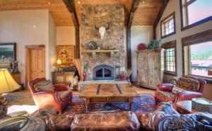 a living room with a stone fireplace and leather furniture at Antler Ridge Lodge in Big Sky