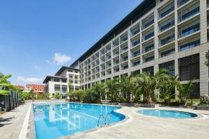 a hotel with a swimming pool in front of a building at Four Points by Sheraton Danzhou in Danzhou