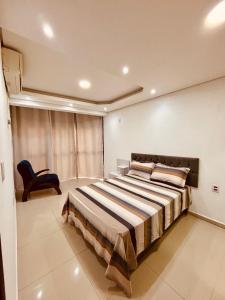 ein Schlafzimmer mit einem großen Bett und einem Stuhl in der Unterkunft Apartamento CENTRO RIO GRANDE in Rio Grande