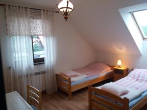 two twin beds in a room with a window at Dom nad Stawem Pokoje Gościnne 