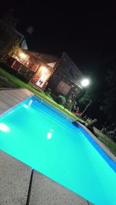 a blue swimming pool at night with a house at La cabaña in Sánchez