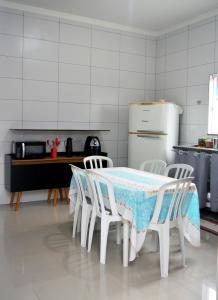 a kitchen with a table and chairs and a refrigerator at Casa Balneário Arpoador in Peruíbe