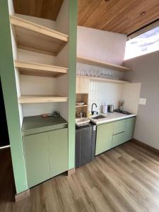 een keuken met groene en witte muren en houten vloeren bij Boreal Glamping in Guatapé