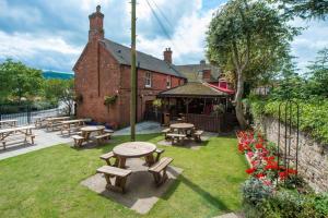 a group of picnic tables in a yard with a building at The bucks head in Church Stretton