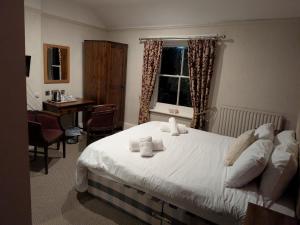 a bedroom with a bed and a desk and a window at The bucks head in Church Stretton