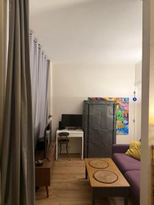 ein Wohnzimmer mit einem lila Sofa und einem Schreibtisch in der Unterkunft Charmant appartement vue jardin in Neuilly-sur-Seine