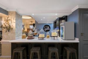 a kitchen with a counter with stools and a refrigerator at Protea Hotel by Marriott Johannesburg Balalaika Sandton in Johannesburg