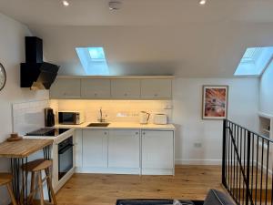 a kitchen with white cabinets and two skylights at Tiny House in Cosy Village in Milnathort