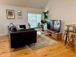 a living room with a black couch and a television at Tiny House in Cosy Village in Milnathort