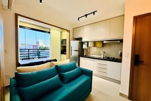 Una sala de estar con un sofá azul y una cocina. en Studio New Home | Praticidade em um Só Lugar, en Uberlândia