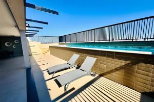 Un balcón con sillas y una piscina. en Studio New Home | Praticidade em um Só Lugar, en Uberlândia