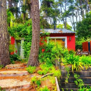 a small red house in the middle of trees at La Unión in Mar Azul
