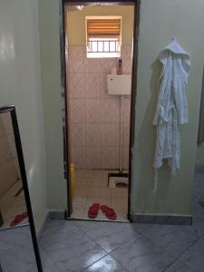 a bathroom with a door open to a bathroom with red shoes at Masaka Haven in Masaka