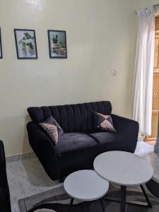 a living room with a black couch and two tables at Masaka Haven in Masaka