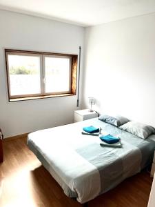a white bedroom with a large bed with blue pillows on it at CALIFORNIA dream in Peniche +4 photos