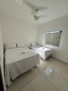 a white room with two beds and a window at Casa aconhegante e cheirosa in Nanuque