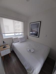 a bedroom with a white bed and a window at Quark Apartments in Lima