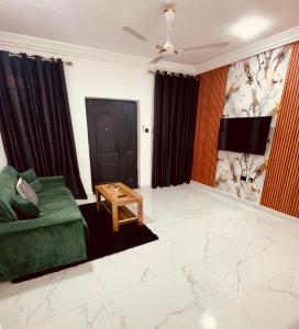 a living room with a green couch and a table at Modern 1 Bedroom Ground Floor Apartment with Serene Mountain Views, close to Aburi Walking Trail in Oyarifa +8 photos