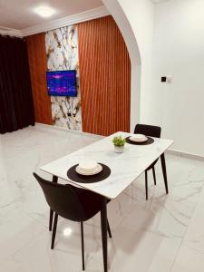 a dining table with two chairs and a white table at Modern 1 Bedroom Ground Floor Apartment with Serene Mountain Views, close to Aburi Walking Trail in Oyarifa