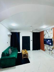 a living room with a green couch and a table at Modern 1 Bedroom Ground Floor Apartment with Serene Mountain Views, close to Aburi Walking Trail in Oyarifa