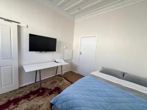 a bedroom with a bed and a desk with a tv on the wall at Bluewater Lodge in Napier