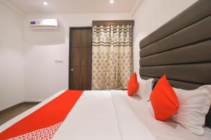 a bedroom with a bed with red and white pillows at Hotel O Rudraksh in Indore