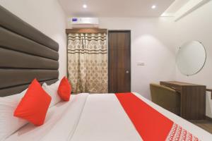 a bedroom with a large bed with red pillows at Hotel O Rudraksh in Indore