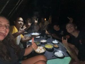 a group of people sitting around a table eating food at Ma2 Jo2 Guest House Explore Jungle Track AND Transportation in Bukit Lawang
