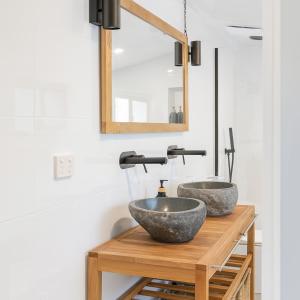 une salle de bain avec deux lavabos en granit sur une table en bois dans l'établissement Surveyor's Cottage, à Surveyors Bay