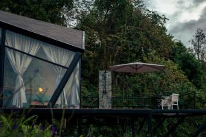 a house with an umbrella and a table and chairs at Glamping Santuario in Calarcá