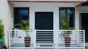 a house with a white fence and two potted plants at The Best In Accra Modern 1 Bedroom Stylish & Private Oyarifa Escape with Breathtaking Mountain Views Fast WiFi Onsite Security Minutes from Top Restaurants Shops And Essentials Airport Pickup City Tours Book Now in Oyarifa